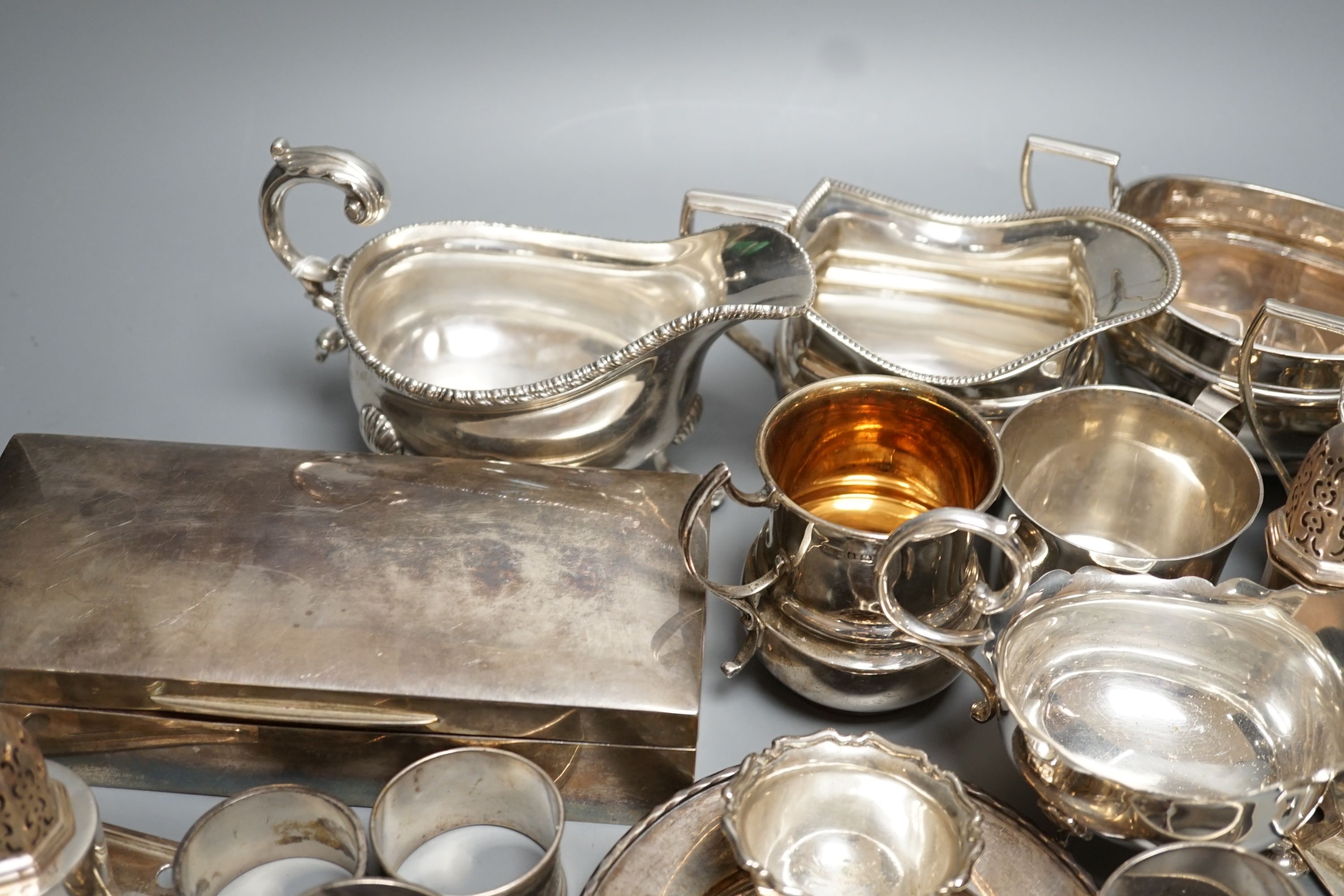 A quantity of assorted mainly 20th century sundry silver including three cream jugs, two silver sauceboats, two small mugs, pair of pepperettes, cigarette box, two match sleeves, pair of salts, seven napkin rings, two sc